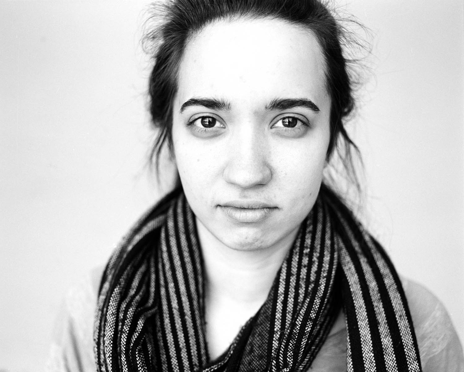 Black and white headshot portrait of a girl against a white background. Photographed with a Mamiya RB67