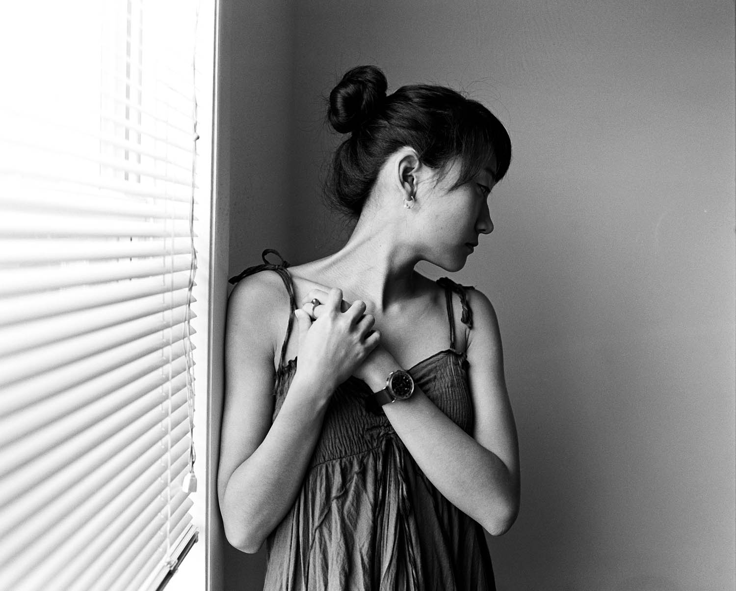 Black and white portrait of a girl standing near window blinds. Photographed on a Mamiya RB67