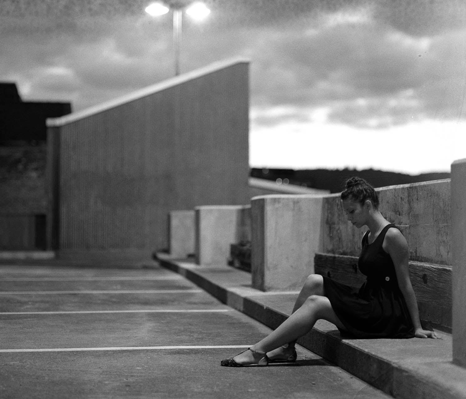 Black and white photograph of a girl sitting on a rooftop, photographed with a Pentax 67