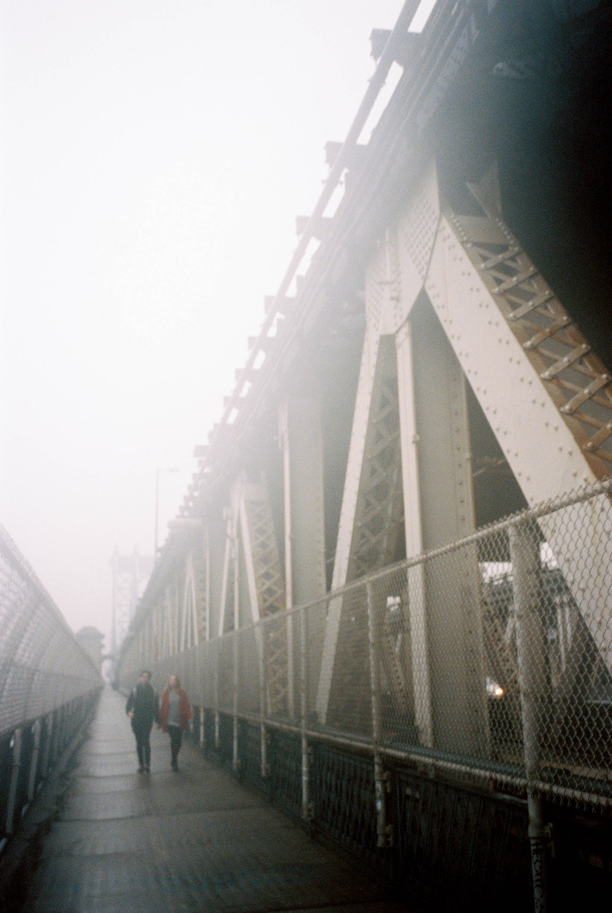 A couple walking down a foggy NYC bridge