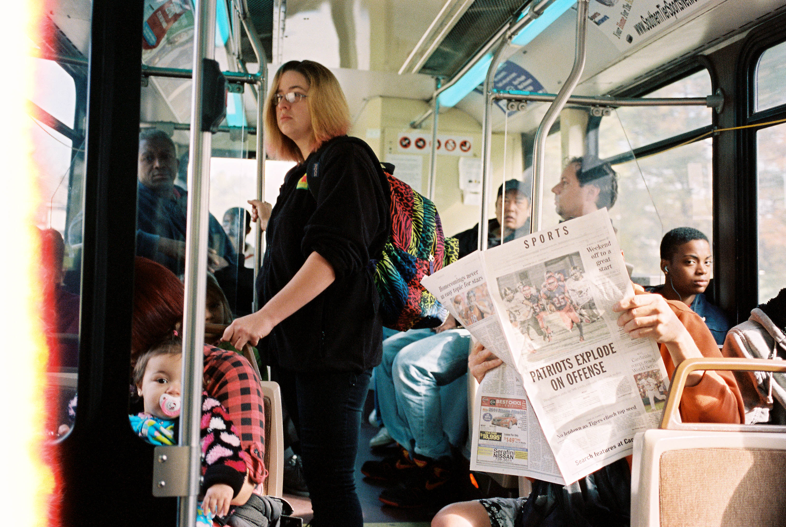 A man reading the newspaper on a crowded Binghamton, NY city bus