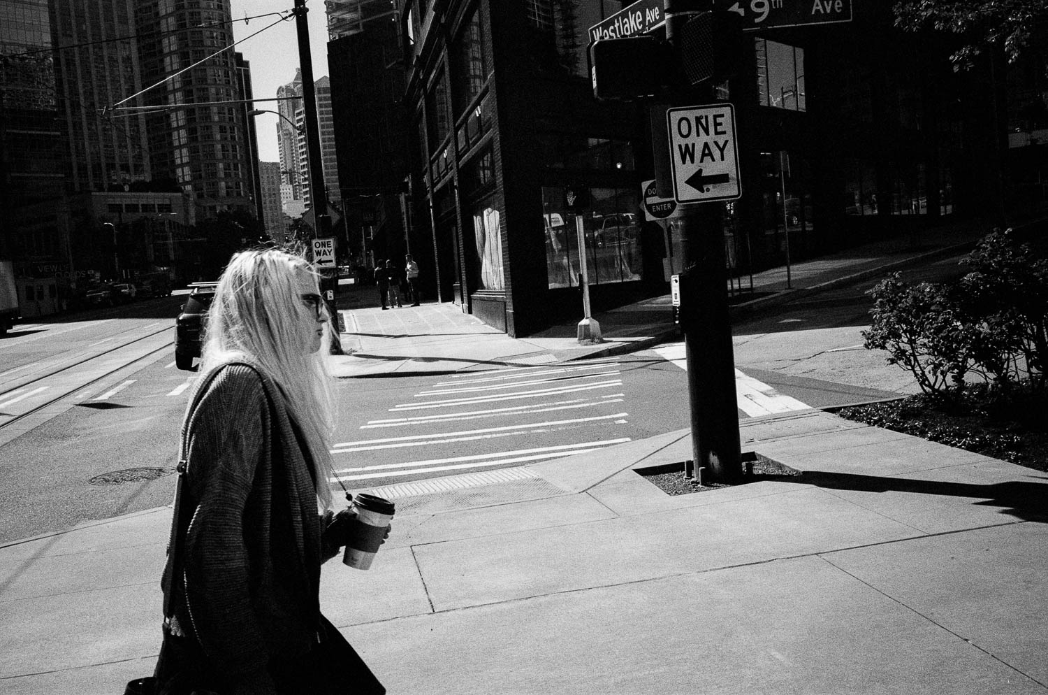 A girl walking across a sidewalk with a coffee cup in hand