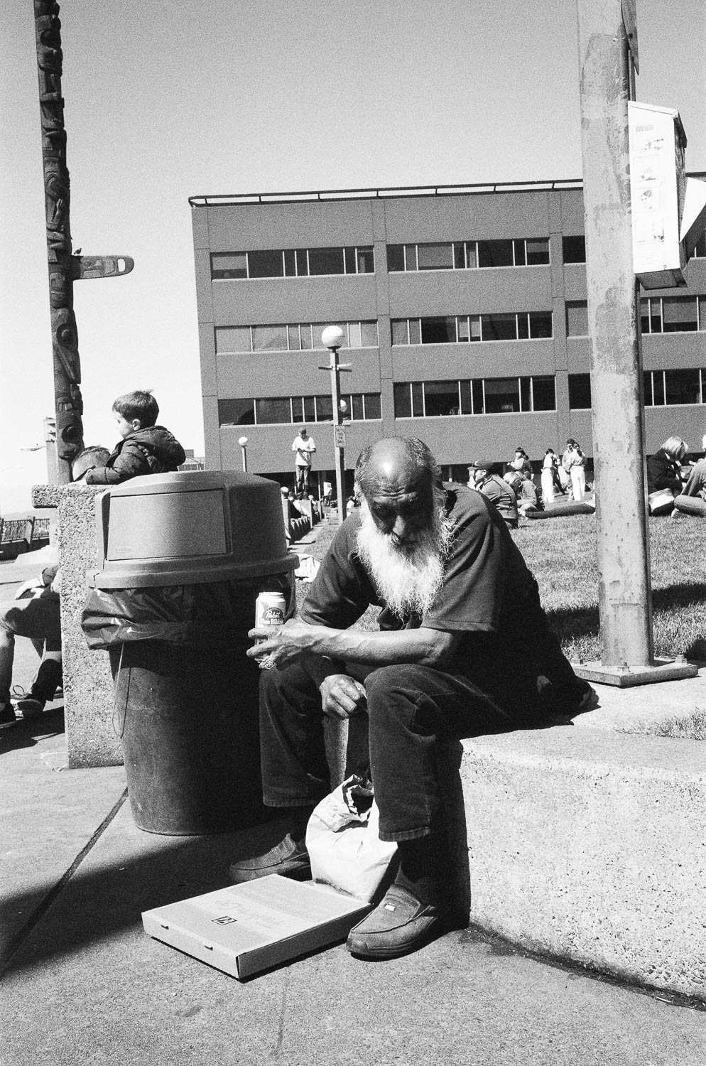 A bald, bearded man sitting in a public Seattle park