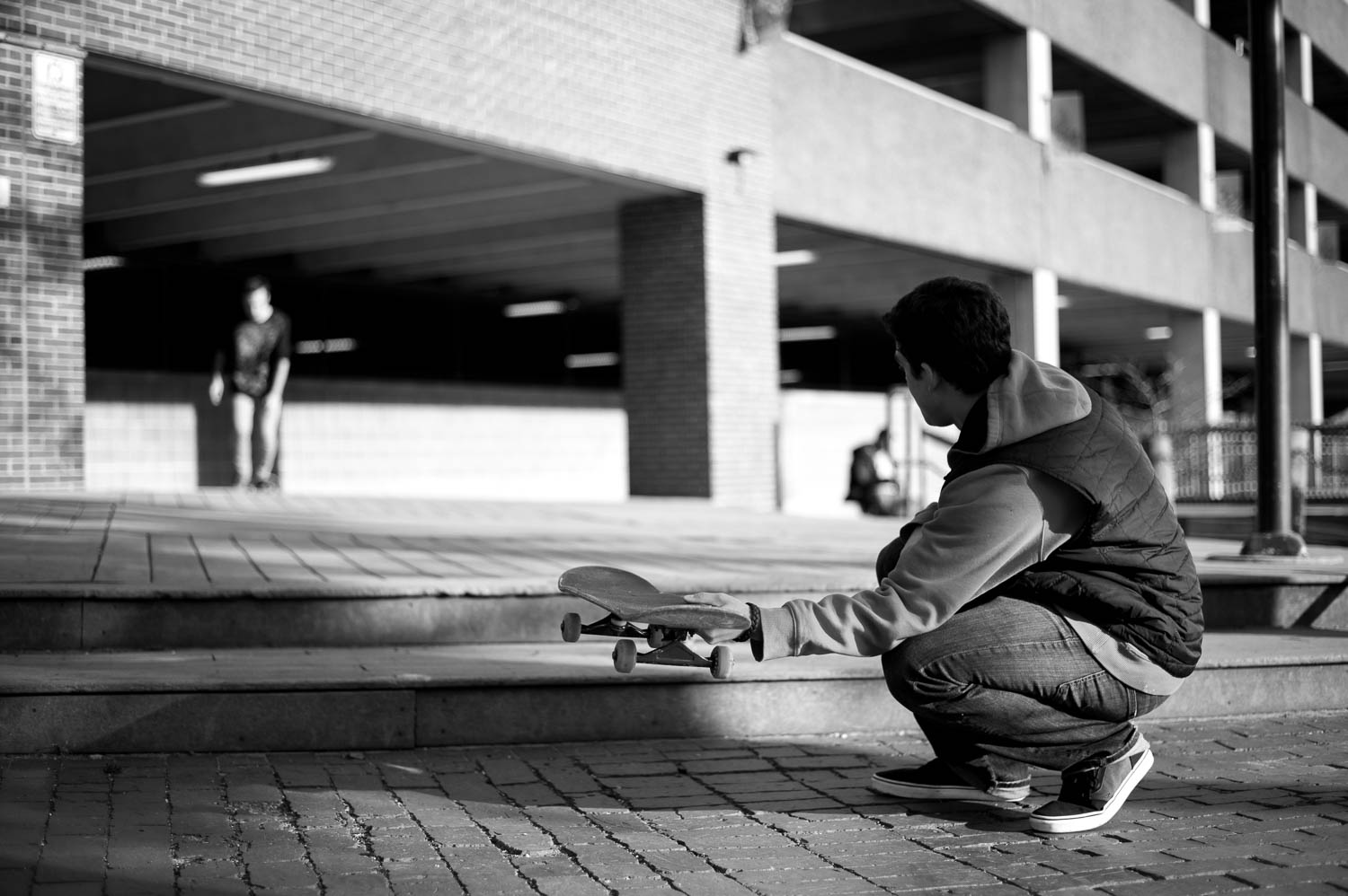 A skateboarder holds his board up in the air for his friend to jump on