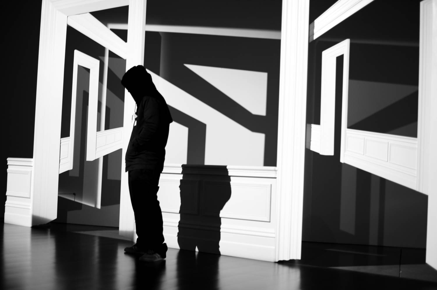 A figure stands in front of an art exhibit at ICA Boston with harsh shadows