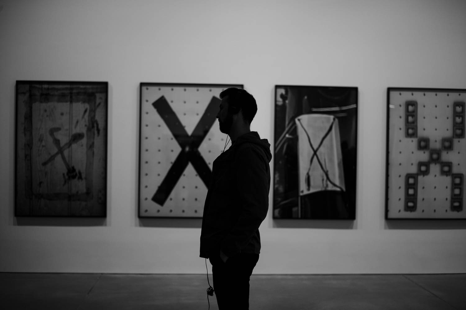 A man standing in front of four large prints of photographs of X-shapes
