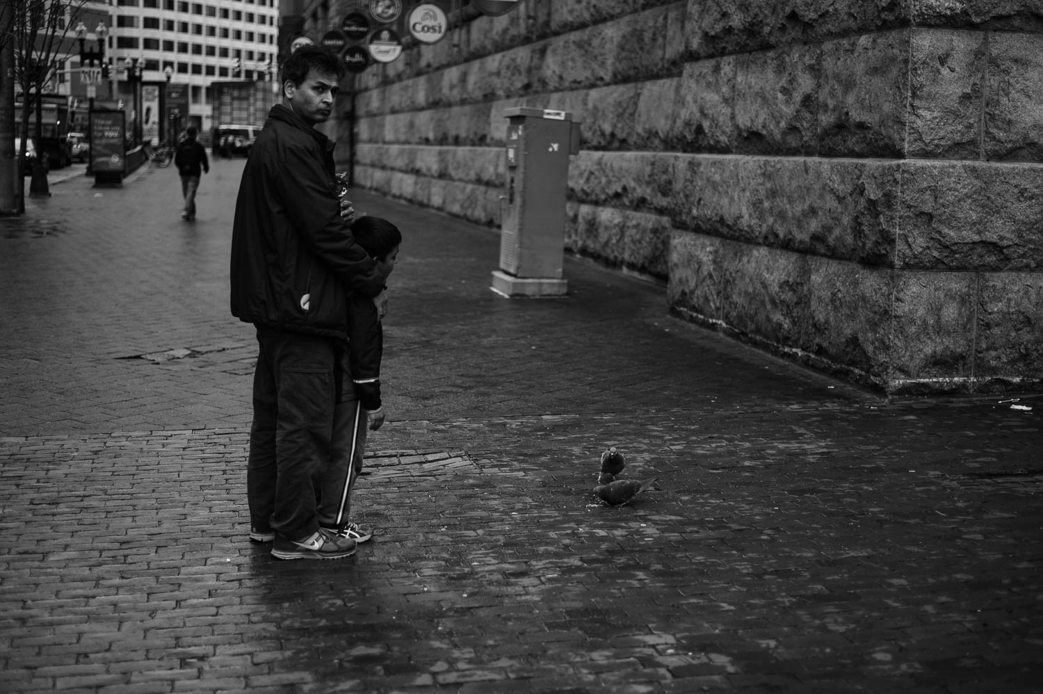 A man and his son feed pigeons in Boston