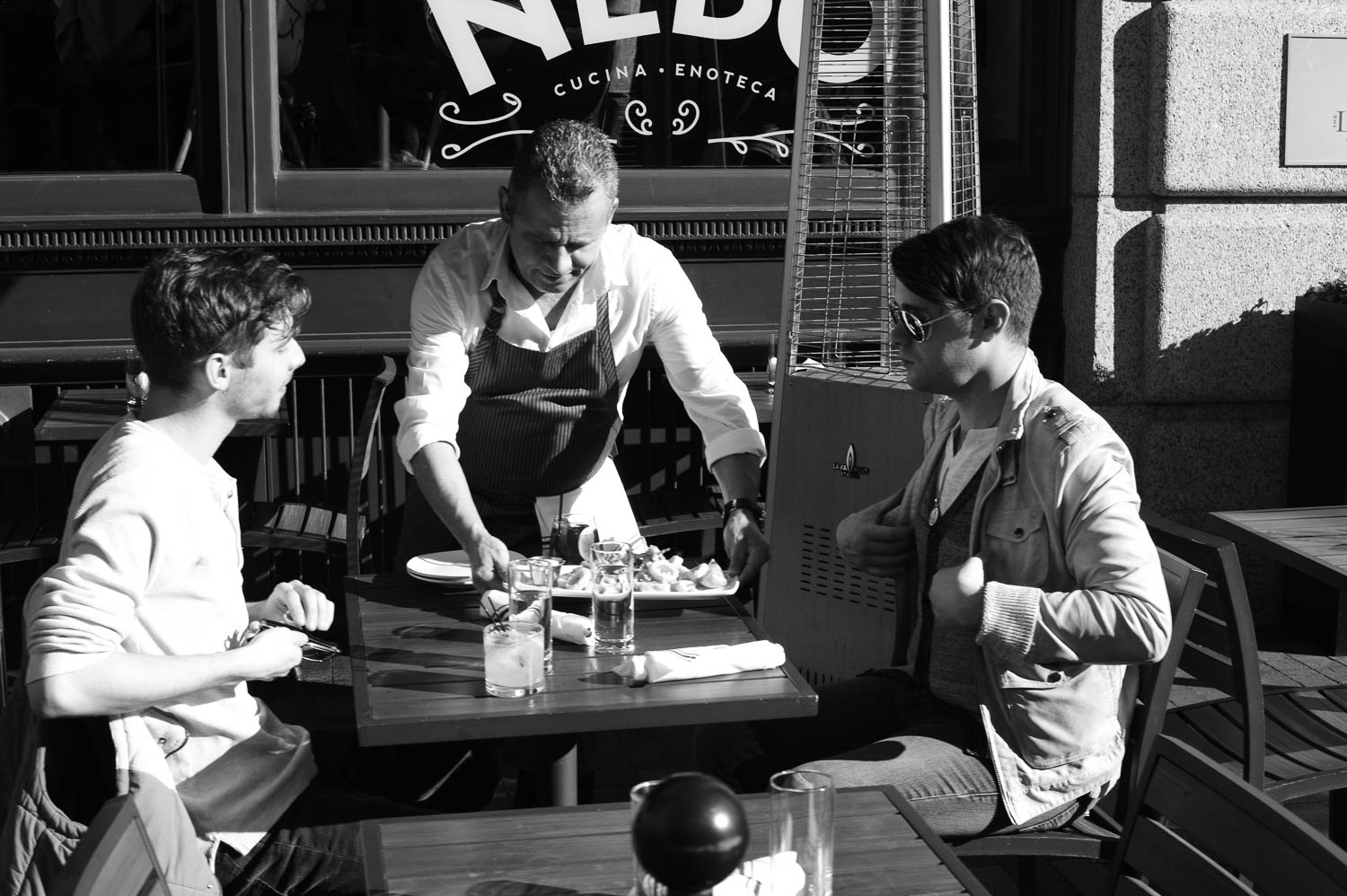 A waiter serves two men at an outdoor table in Boston
