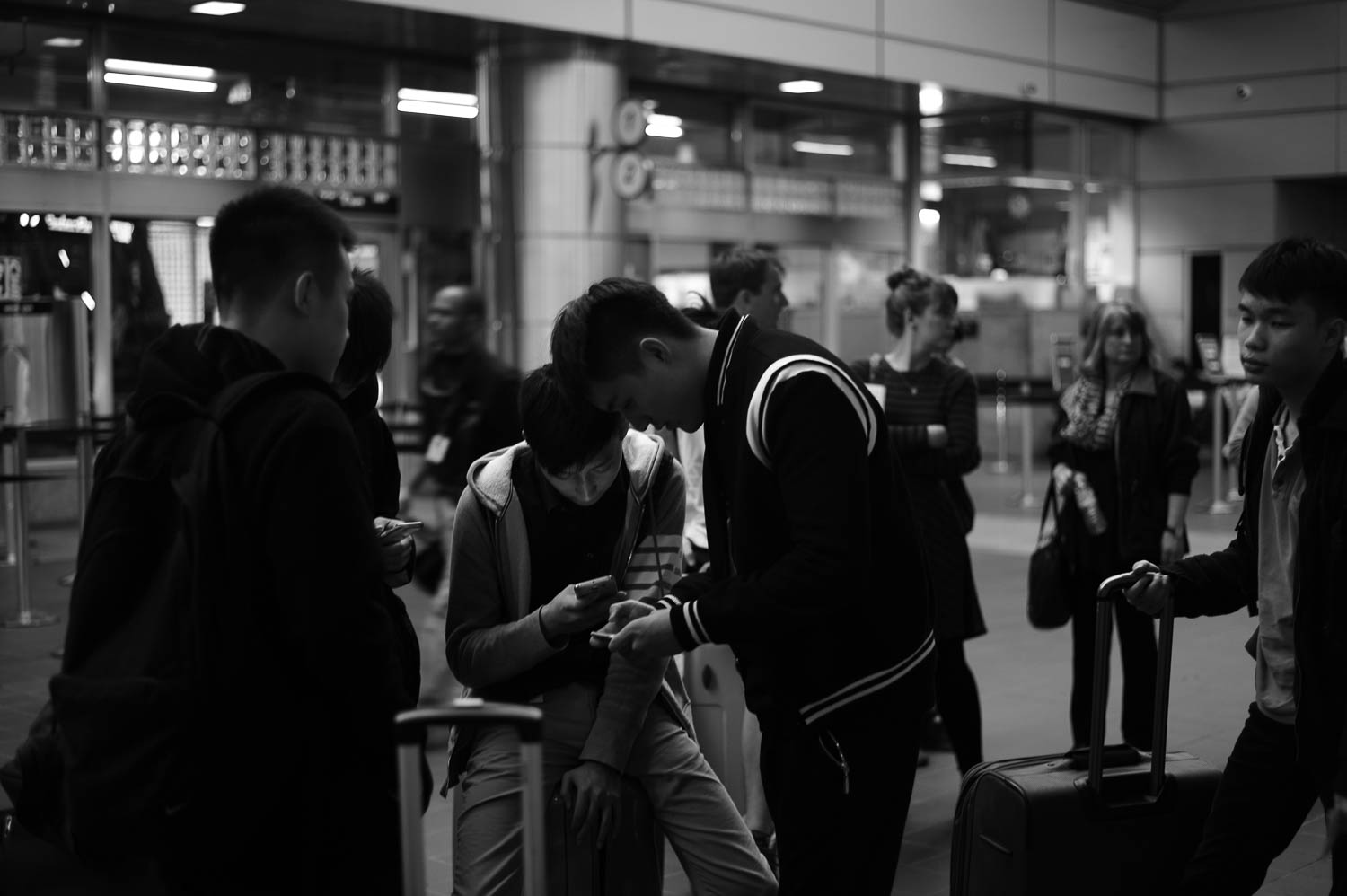 A small crowd peer into smartphones with luggage surrounding them at Boston's South Station