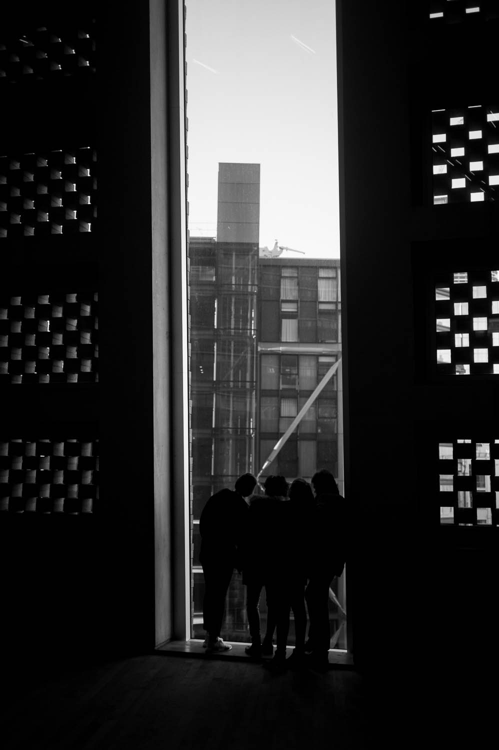 A group of children look through a tall window at the Tate Modern museum.