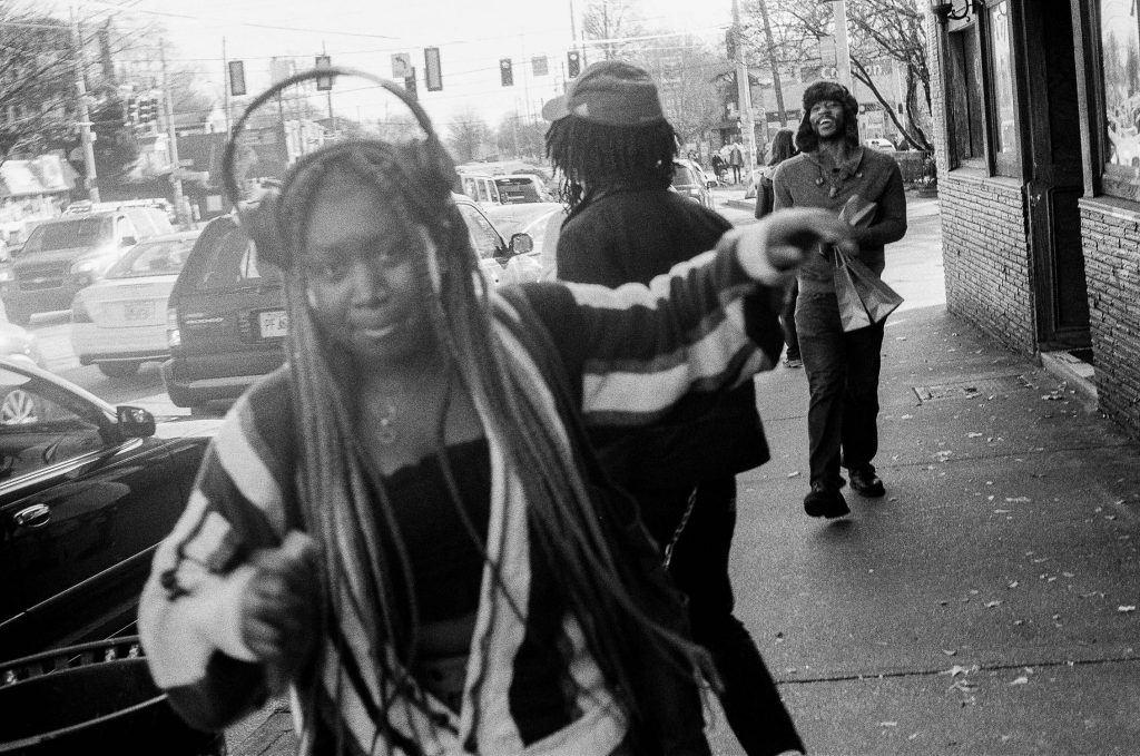 A woman dancing casually on the street with headphones high up on her head