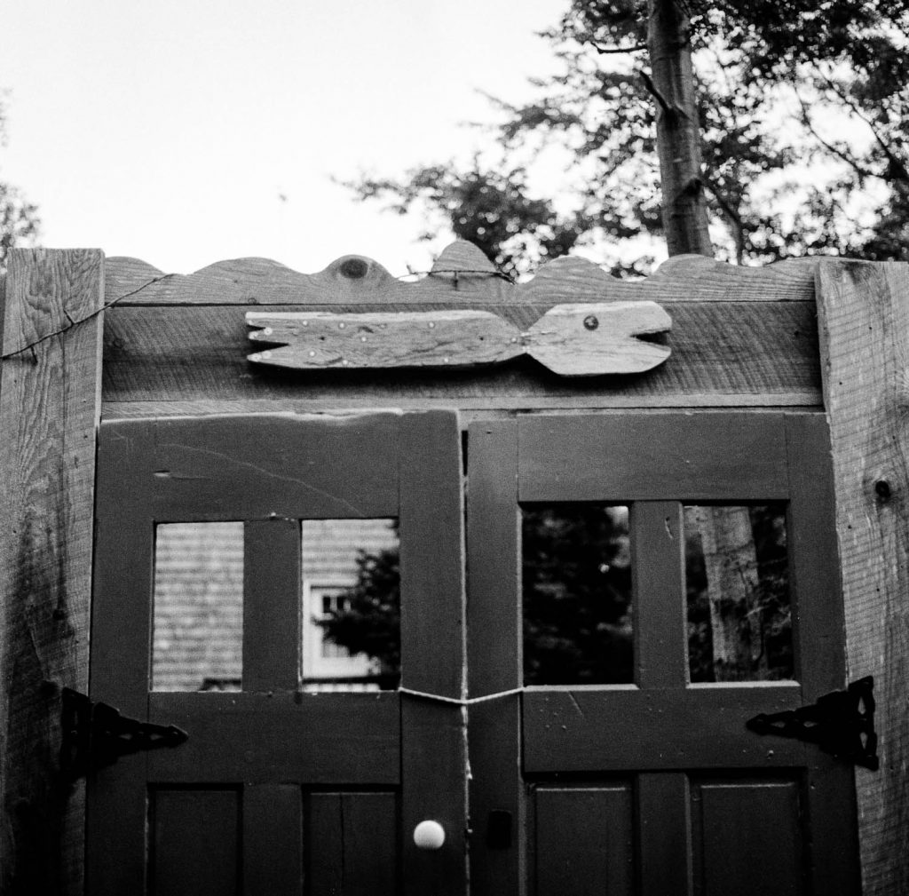 A set of rustic double doors with a simple carved wooden fish above them on Peaks Island